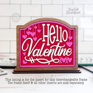 May include: A wooden Valentine's Day sign with a red background and the words "Hello Valentine" in white script. Pink hearts dangle from the top. The sign is layered with a pink border and a brown wooden frame.