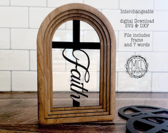 Puede incluir: Un marco de madera arqueado con un inserto de cruz negra que presenta la palabra Faith en cursiva. El texto en la imagen dice: Interchangeable digital Download SVG & DXF. File includes frame and 7 words. Un logotipo circular dice MEL Denver.