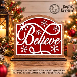 Op de afbeelding: Een houten bord-inzetstuk met een rode achtergrond, het woord Believe in witte cursieve letters en witte sneeuwvlokken. De tekst Mel Denver Designs Digital Download is rechtsboven zichtbaar. Dit inzetstuk is bedoeld voor een verwisselbaar frame.