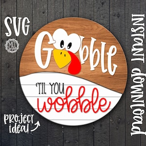 May include: A round wooden sign with a white turkey design. The turkey has a red wattle and a yellow beak. The sign says "Gobble til you wobble" in white and red lettering. The sign is a project idea.