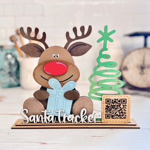 May include: Wooden Santa tracker with a reindeer holding a gift, a green Christmas tree, and a QR code. The base of the tracker says "Santa Tracker".