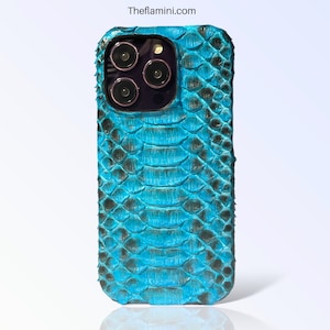 Pode incluir: Capa de telefone texturizada turquesa e preta com padrão de pele de cobra. A capa cobre a parte traseira e as laterais do telefone. As lentes da câmera do telefone são visíveis.