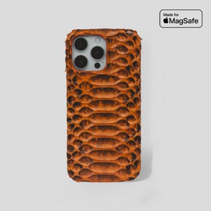 Könnte beinhalten: Braune Handyhülle mit Schlangenleder-Textur. Die rechteckige Hülle hat einen Kameraausschnitt und den Text "Made for MagSafe" in einem weißen Rechteck.