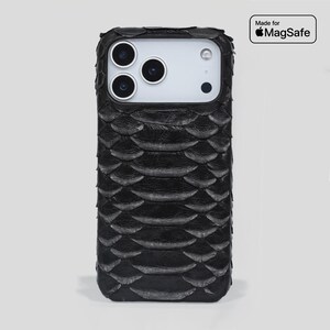 以下が含まれることがあります： 黒色の質感のある携帯電話ケース。鱗のような模様があります。ケースは角が丸い長方形で、カメラ用の切り欠きがあります。ケースの右上隅には「Made for MagSafe」というテキストがあります。