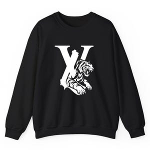 May include: Black sweatshirt with a white graphic. The graphic features a stylized letter "X" with a roaring tiger design. The tiger is in a detailed, black and white illustration. The sweatshirt has long sleeves and a crew neck.