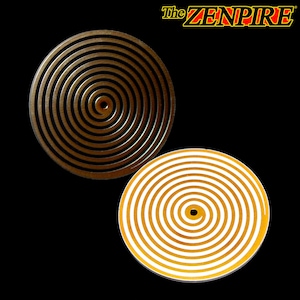 Könnte beinhalten: Zwei runde Untersetzer mit einem Spiraldesign. Ein Untersetzer ist metallisch goldfarben, der andere ist weiß mit goldenen Spiralen. Die Untersetzer sind vor einem schwarzen Hintergrund platziert, mit dem Text "The ZENPIRE" oben rechts.