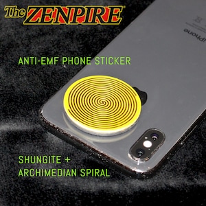 Peut inclure: Un autocollant de téléphone anti-EMF jaune et noir avec un motif en spirale d'Archimède est fixé au dos d'un smartphone argenté. L'autocollant est rond et porte le texte "ANTI-EMF PHONE STICKER". La marque "The ZENPIRE" est en haut.