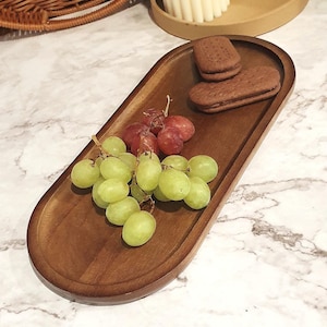 May include: A wooden oval serving tray with a dark brown finish. The tray is filled with green grapes and chocolate sandwich biscuits.