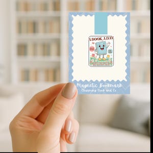 May include: A magnetic bookmark with a light blue border and a cartoon book character. The bookmark reads "A Book A Day" and "Keeps the Mental Breakdown Away." The text "Read More" and "Cry Less" are also included.