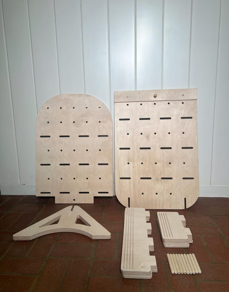 May include: A set of unfinished wooden pieces for building a jewellery organiser. The set includes two large panels with holes, a triangular base, and several smaller pieces for shelves and dowels.