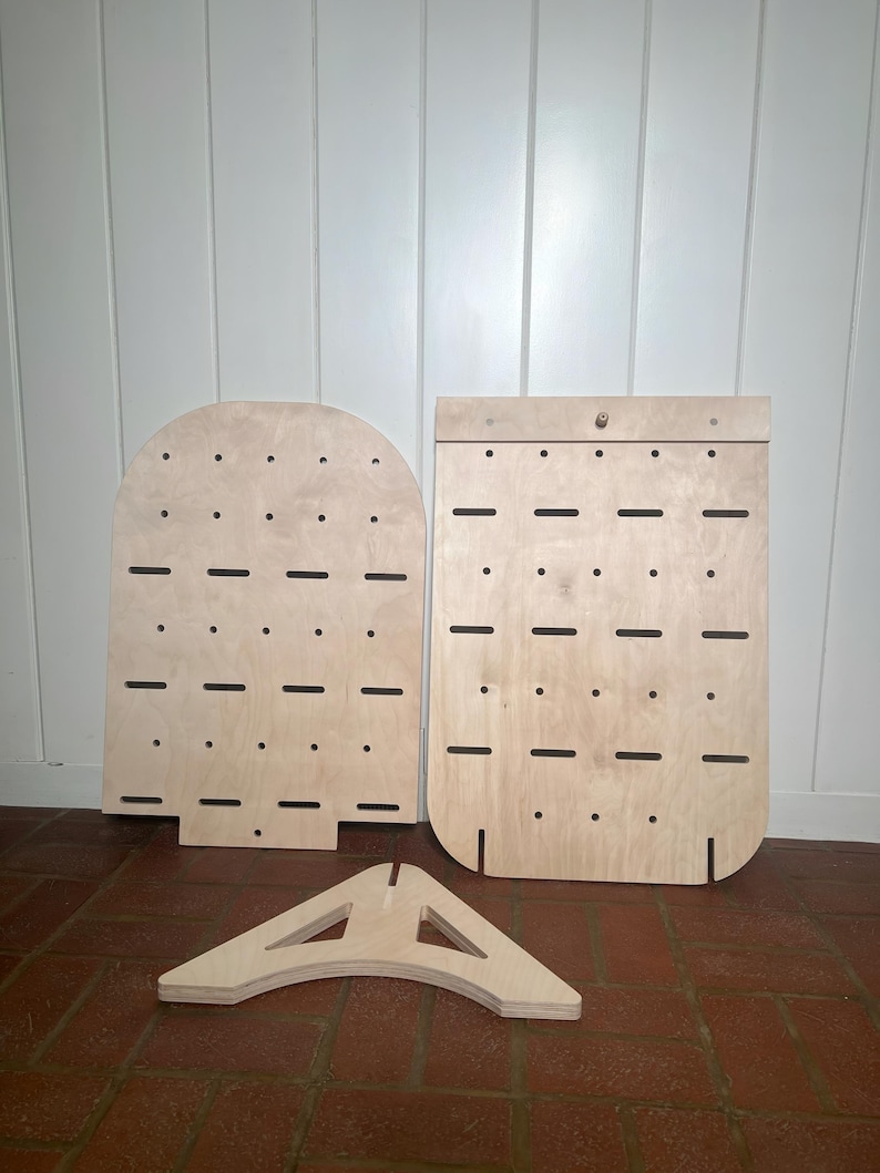 May include: Three pieces of unfinished wood, two are rectangular with holes and one is a triangular stand. The wood is light brown and has a smooth surface.