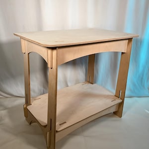 Könnte beinhalten: Ein helles Holz-Beistelltisch mit rechteckiger Oberseite und einem unteren Regal. Der Tisch hat ein schlichtes, modernes Design mit gewölbten Stützen und ist aus hellem Holz gefertigt. Der Tisch ist etwa 61 cm hoch.
