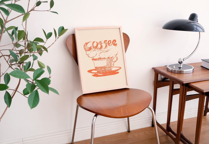 May include: A framed print with a cream background and a red illustration of a coffee cup with steam that reads "Coffee".