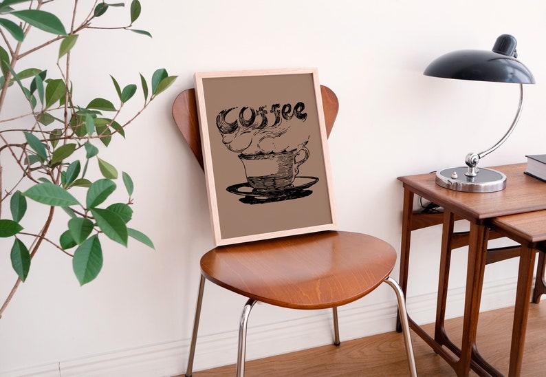 May include: A framed print of a black and white illustration of a coffee cup with steam rising from it. The word "Coffee" is written in a stylized font above the cup.