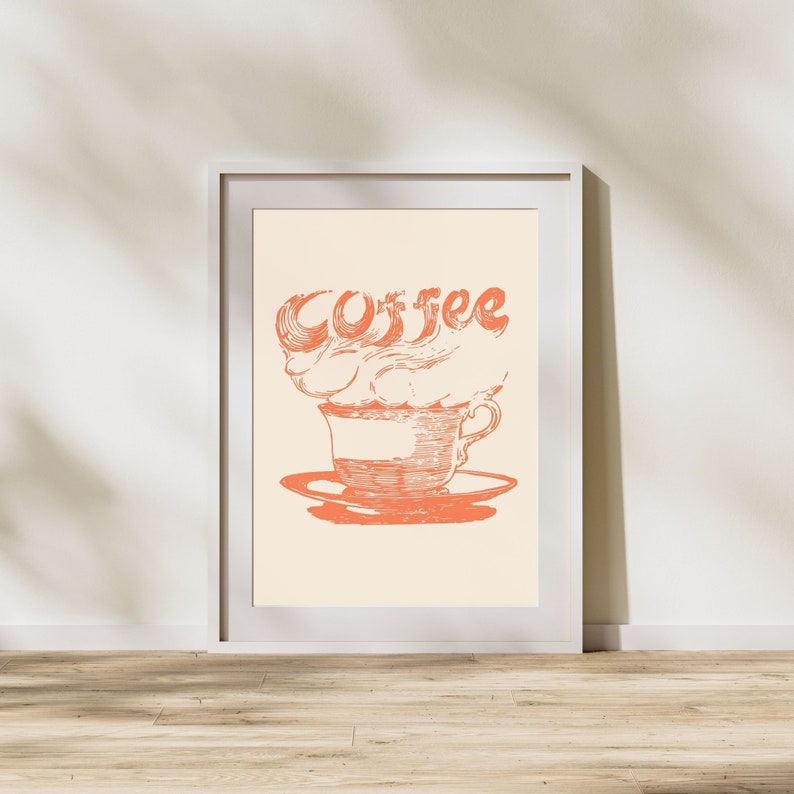 May include: A framed print with a vintage illustration of a coffee cup with steam rising from it. The steam is shaped like the word "Coffee" in a stylized font. The print is on a cream background with a white frame.