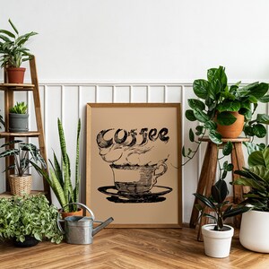 May include: A white wall with a wooden shelf unit holding various potted plants. A framed print with a black and white illustration of a coffee cup with steam and the word "Coffee" is hanging on the wall. There are also several potted plants on the floor.