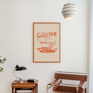 May include: A framed print with a stylized illustration of a coffee cup with steam forming the word "coffee" in red on a cream background.