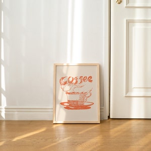 May include: A framed print with a stylized illustration of a coffee cup with steam rising from it. The word "Coffee" is written in a stylized font above the cup.