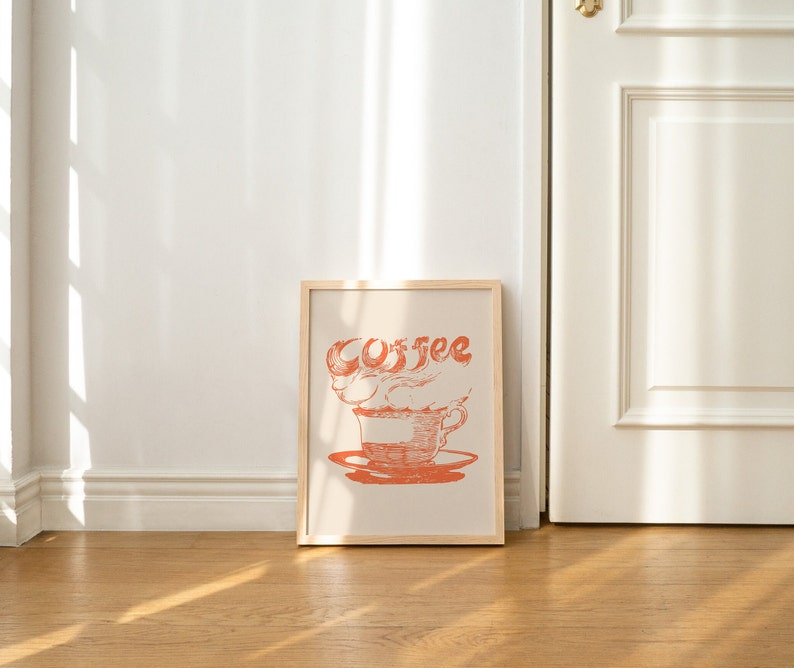 May include: A framed print with a stylized illustration of a coffee cup with steam rising from it. The word "Coffee" is written in a stylized font above the cup.