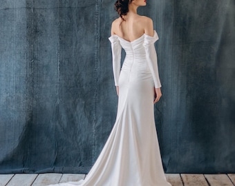 Abito da sposa in seta su misura, con maniche lunghe e spalle scoperte, stile sirena con corsetto drappeggiato.