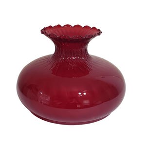 May include: A deep red glass lamp shade with a bulbous, rounded body and a narrow, fluted neck. The top opening features a distinct ruffled, scalloped edge. The surface of the glass is smooth and glossy, reflecting light across its curved form.
