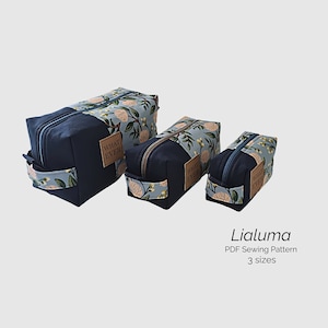 May include: Three blue and white floral zippered pouches with a brown leather patch that says "What Ever" in white lettering. The pouches are in different sizes. The text "Lialuma PDF Sewing Pattern 3 sizes" is below the pouches.