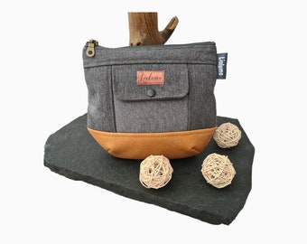 May include: A grey zipped pouch with a brown leather base and a small pocket on the front. The pouch has a brown leather tag with the word "Licluma" printed on it.