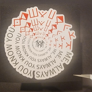 May include: A white sticker with a spiral design of red geometric shapes and text. The text reads "ME, ALWAYS YOU KNOW YOU". The sticker is on a black surface, with a pair of tweezers in the lower right corner.