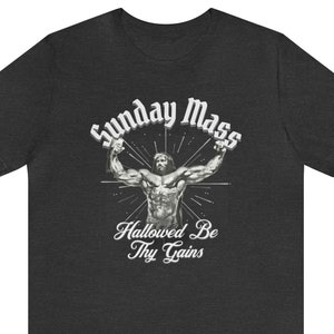 May include: A dark grey t-shirt with a white graphic of a muscular figure with the text "Sunday Mass" and "Hallowed Be Thy Gains".