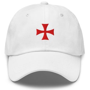 Pode incluir: Boné de beisebol branco com uma cruz vermelha bordada na frente.