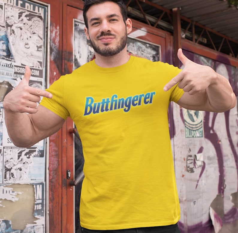 May include: A yellow t-shirt with the text "Buttfingerer" in blue and teal lettering.