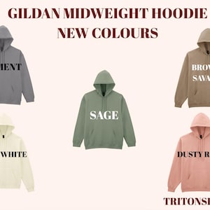 Op de afbeelding: Een display van Gildan midweight hoodies in nieuwe kleuren. De hoodies worden getoond in cement, bruin savana, salie, gebroken wit en dusty rose. Elke hoodie heeft een capuchon en een voorzak. De tekst "GILDAN MIDWEIGHT HOODIE NEW COLOURS" staat bovenaan.