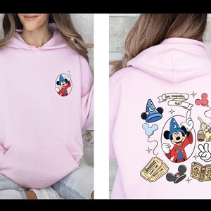 Op de afbeelding: Lichtroze hoodie met een voorzak en een kleine Mickey Mouse-afbeelding op de voorkant. De achterkant toont een groter Mickey Mouse-ontwerp met de tekst "Some imagination, Huh?" en andere cartoon elementen.