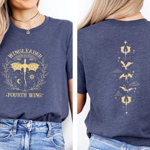 May include: A navy blue t-shirt with a gold graphic of a dragon and the text "WINGLEADER FOURS QUART HEART FOURTH WING". The back of the shirt has a vertical row of gold dragon graphics.