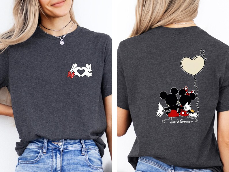 May include: Dark grey t-shirt with a Mickey Mouse and Minnie Mouse design. The front shows hands forming a heart, and the back displays the couple with a heart-shaped balloon. The names "Joe & Samantha" are written below.