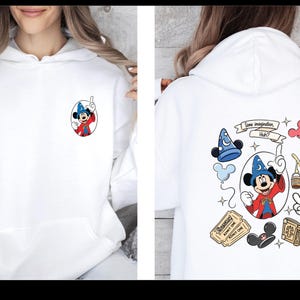 Op de afbeelding: Witte hoodie met een Mickey Mouse-afbeelding op de voor- en achterkant. De voorkant heeft een klein Mickey Mouse-ontwerp. De achterkant heeft een groter ontwerp met Mickey Mouse, een tovenaars hoed en de tekst "Some imagination, Huh?"