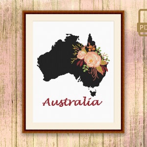 May include: Cross-stitch design of Australia in black, featuring a floral arrangement in peach, burgundy, and green. The word "Australia" is stitched in burgundy. The framed artwork includes a PDF icon.