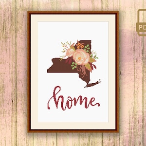 May include: Cross stitch pattern featuring the outline of the state of New York with a floral bouquet in the center and the word "home" written in cursive below. The pattern is in a brown frame.