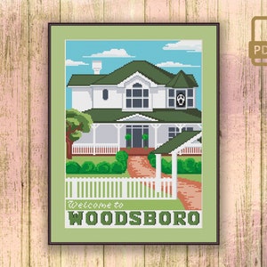 May include: Cross stitch pattern of a white house with a green roof and a white picket fence. The house has a porch and a sign that says "Welcome to Woodsboro".