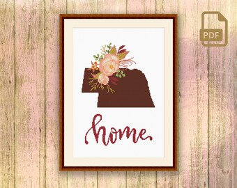 May include: A cross-stitch pattern featuring a floral design with pink flowers and green leaves, a brown silhouette of the state of Oklahoma, and the word "home" in cursive script.