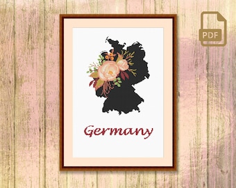 May include: A cross-stitch pattern of the outline of Germany with a floral bouquet in the top left corner. The text "Germany" is below the outline.