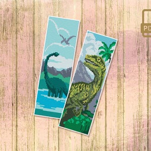 May include: Two cross-stitch bookmark patterns featuring dinosaurs. The first bookmark shows a green dinosaur with a long neck standing in a blue body of water. The second bookmark shows a green dinosaur with a long tail and a pointed snout standing in a green jungle.