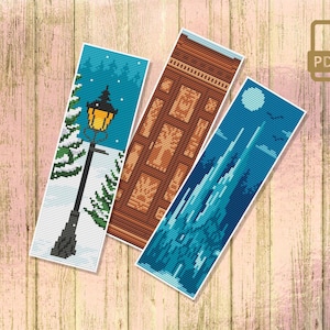 Puede incluir: Tres patrones de marcapáginas de punto de cruz que representan una escena de invierno con una farola, una puerta de madera y un castillo azul. Los patrones están impresos en papel y llevan la etiqueta "PDF".