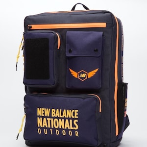May include: A navy blue backpack with orange accents and multiple pockets. The backpack has a large pocket on the front with the text "NEW BALANCE NATIONALS OUTDOOR" in yellow lettering.
