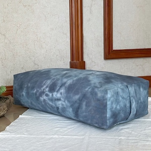 Peut inclure: Un coussin de méditation bleu et blanc tie-dye. Le coussin est rectangulaire et possède une fermeture éclair sur un côté.