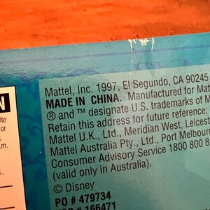 May include: A blue product packaging label featuring black text that reads Mattel, Inc. 1997, El Segundo, CA 90245, MADE IN CHINA. Manufactured for Mattel. Retain this address for future reference: Mattel U.K., Ltd., Mattel Australia Pty., Ltd. Disney PO # 479734 FSC # 166471.