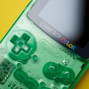 Op de afbeelding: Een draagbare Game Boy Color spelcomputer met een doorschijnende neongroene plastic behuizing. Het apparaat toont het Nintendo-logo en de tekst Game Boy Color op de schermrand, met zichtbare interne circuits, een richtingspad en diverse knoppen.