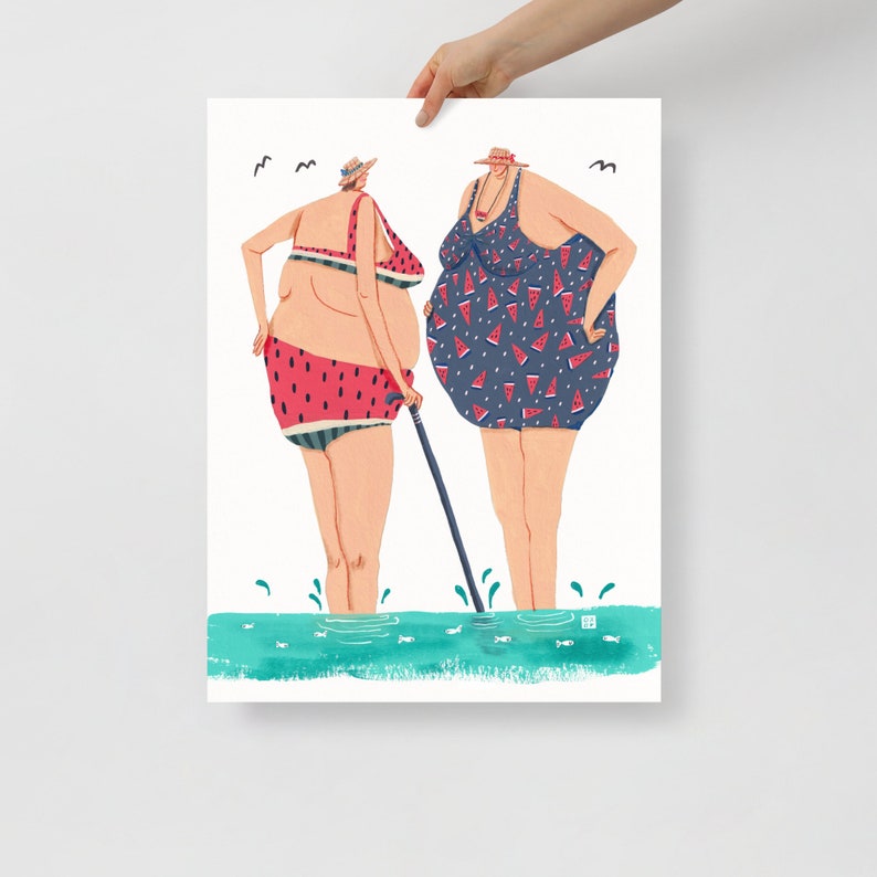 May include: Two women in swimsuits stand in the water. One woman is wearing a watermelon print swimsuit and the other is wearing a blue swimsuit with watermelon slices printed on it. The woman in the watermelon print swimsuit is holding a cane.