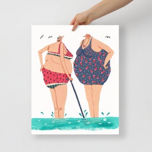 May include: Two women in swimsuits stand in the water. One woman is wearing a blue swimsuit with a watermelon print and the other is wearing a red and white watermelon print swimsuit. Both women are wearing hats.