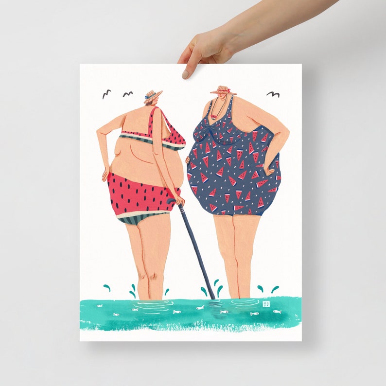 May include: Two women in swimsuits stand in the water. One woman is wearing a blue swimsuit with a watermelon print and the other is wearing a red and white watermelon print swimsuit. Both women are wearing hats.